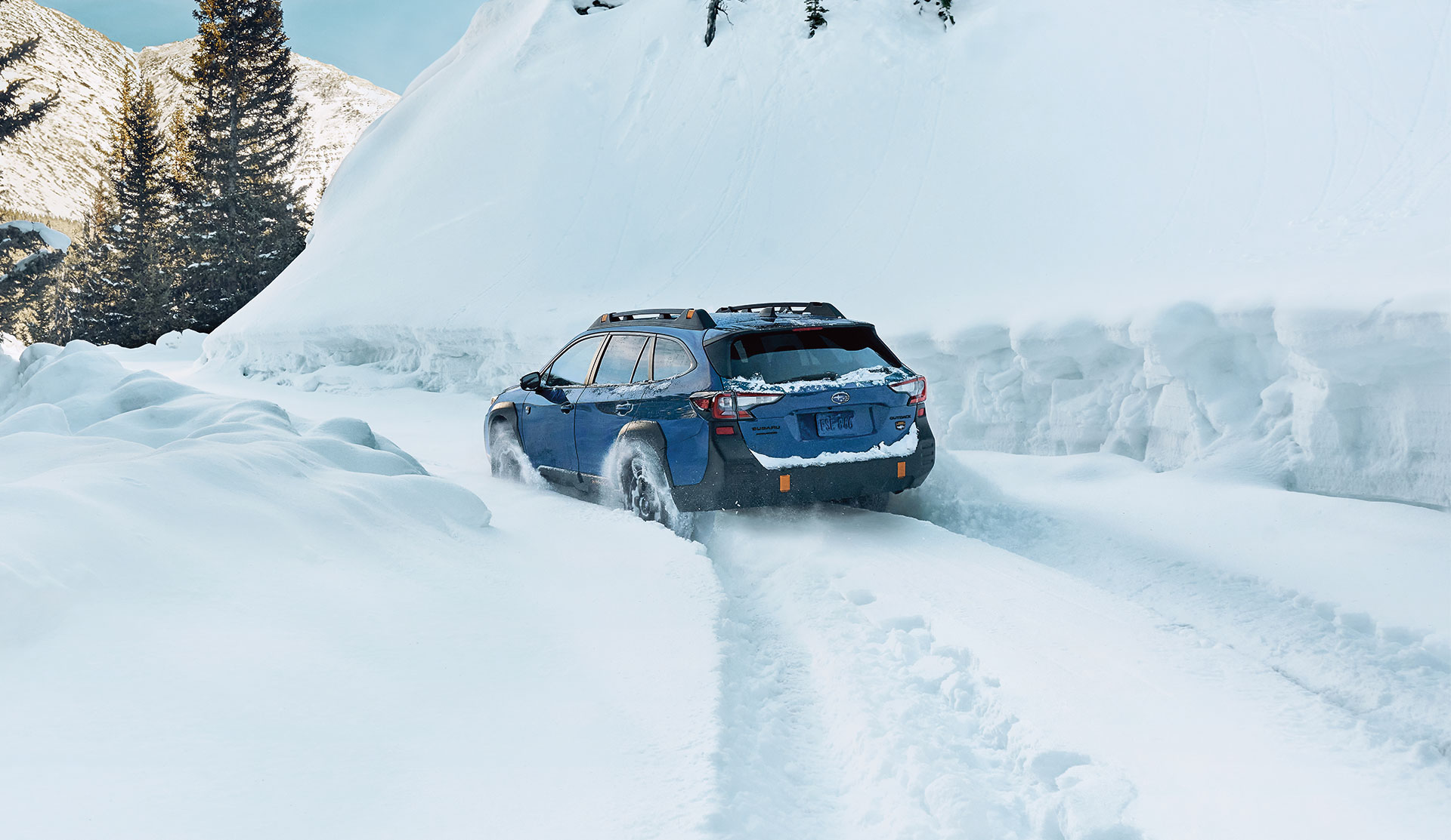 Subaru Outback Wilderness 2025 Vue arrière d’une Outback Wilderness 2025 roulant dans un épais couvert de neige.